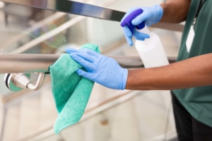Janitorial and disinfection services associate disinfecting a handrail in a commercial workplace